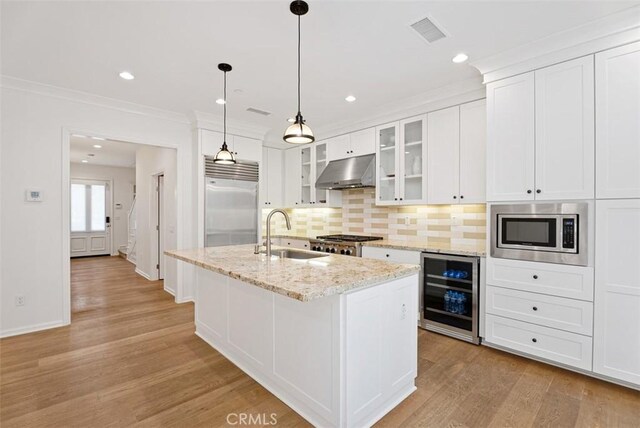 kitchen featuring white cabinetry, sink, wine cooler, built in appliances, and a center island with sink