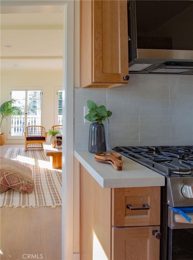 kitchen with backsplash, extractor fan, and stainless steel range with gas stovetop