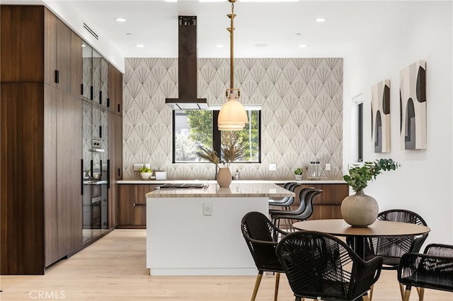 kitchen with decorative backsplash, extractor fan, decorative light fixtures, and light wood-type flooring