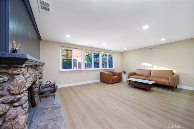 living room featuring a stone fireplace and light hardwood / wood-style floors