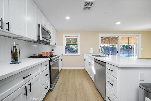 kitchen with white cabinets, appliances with stainless steel finishes, light hardwood / wood-style floors, and sink