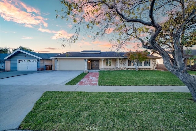 ranch-style house featuring a lawn, solar panels, and a garage