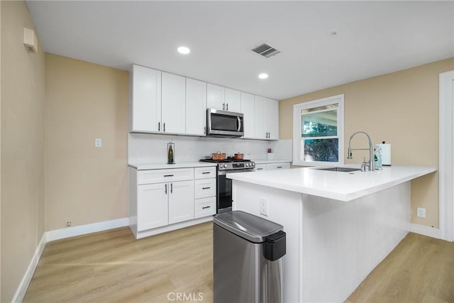 kitchen with white cabinets, stainless steel appliances, light hardwood / wood-style floors, and sink