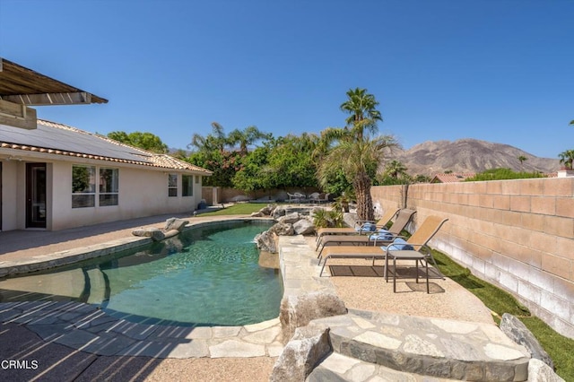 view of pool featuring pool water feature, a mountain view, and a patio area