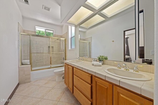 full bathroom featuring tile patterned floors, vanity, enclosed tub / shower combo, and toilet