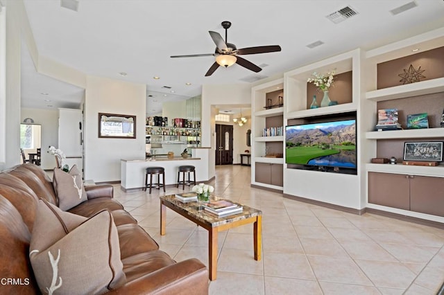 tiled living room with ceiling fan with notable chandelier and built in features