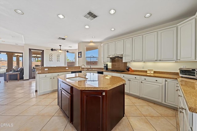 kitchen with a healthy amount of sunlight, white cabinetry, and an island with sink