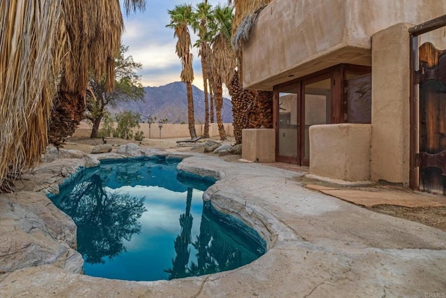 pool at dusk featuring a patio area and a mountain view