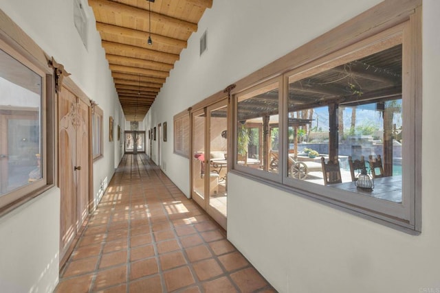 hall with lofted ceiling with beams, wooden ceiling, tile patterned flooring, and a barn door