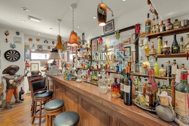 bar featuring light hardwood / wood-style flooring and decorative light fixtures