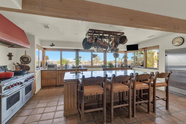 kitchen featuring a wealth of natural light, high quality appliances, custom exhaust hood, and light tile patterned floors