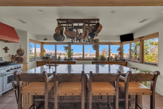 kitchen featuring light tile patterned flooring, custom exhaust hood, stainless steel appliances, and sink