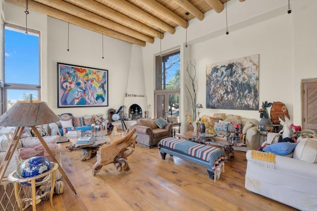 living room with beamed ceiling, wood-type flooring, and a high ceiling