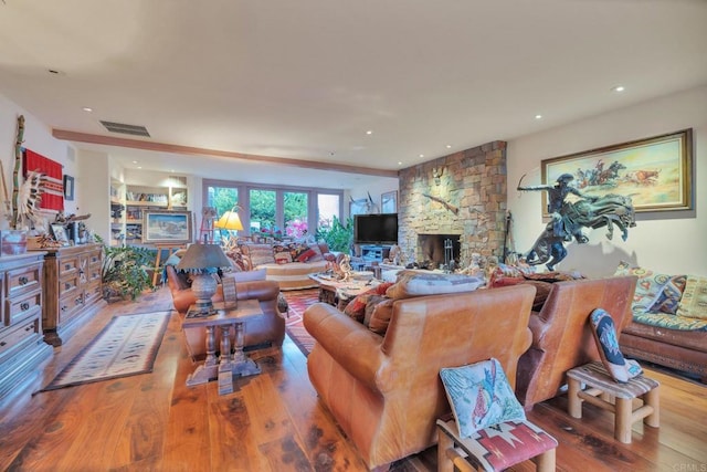 living room with a stone fireplace and hardwood / wood-style flooring