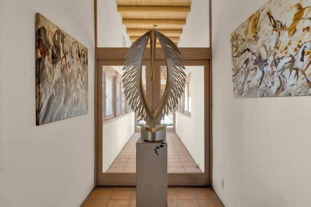 hallway featuring beam ceiling and light tile patterned flooring