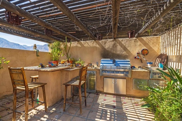 view of patio with area for grilling, exterior bar, a mountain view, and a grill