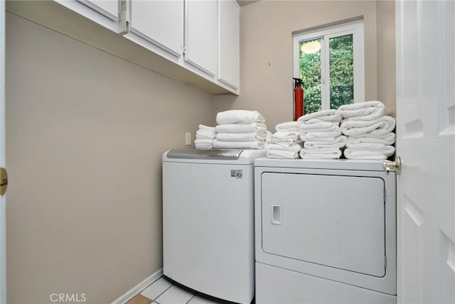 laundry area featuring separate washer and dryer, light tile patterned floors, and cabinets