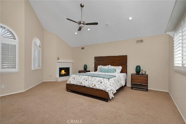 carpeted bedroom featuring high vaulted ceiling, ceiling fan, and a tiled fireplace