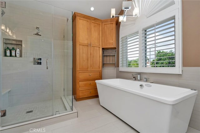 bathroom featuring separate shower and tub, tile patterned floors, a chandelier, and tile walls