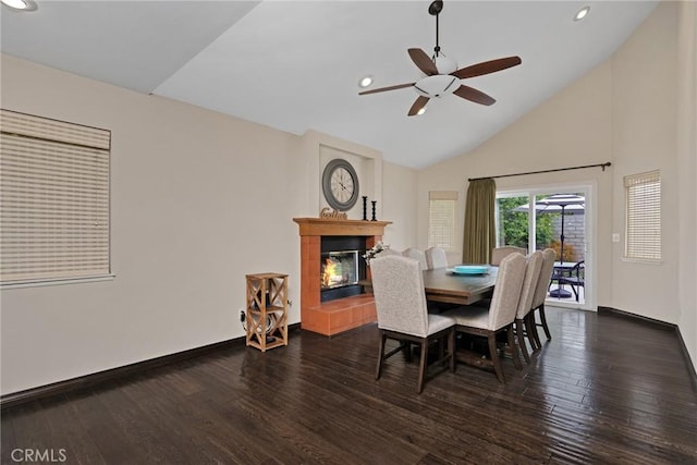 dining space featuring dark hardwood / wood-style flooring, ceiling fan, a fireplace, and high vaulted ceiling