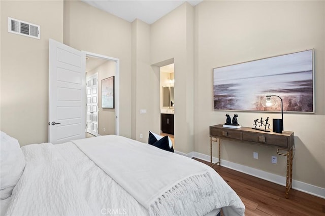 bedroom with ensuite bathroom and dark hardwood / wood-style flooring