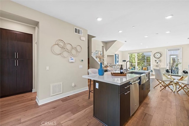 kitchen featuring dishwasher, a center island with sink, light hardwood / wood-style floors, and sink