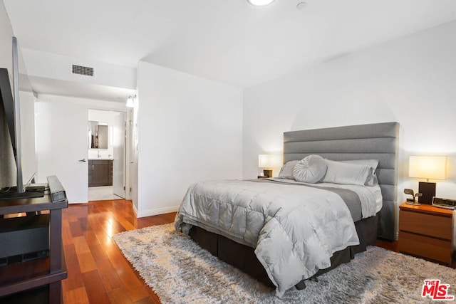 bedroom featuring ensuite bath and wood-type flooring