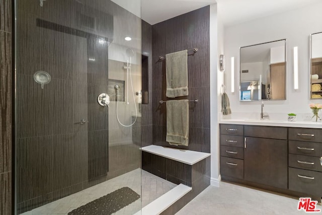 bathroom with a tile shower and vanity