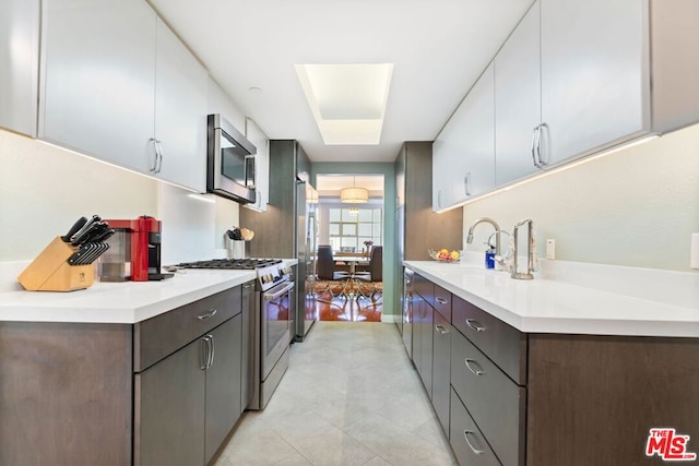 kitchen with sink, white cabinetry, dark brown cabinetry, and stainless steel appliances