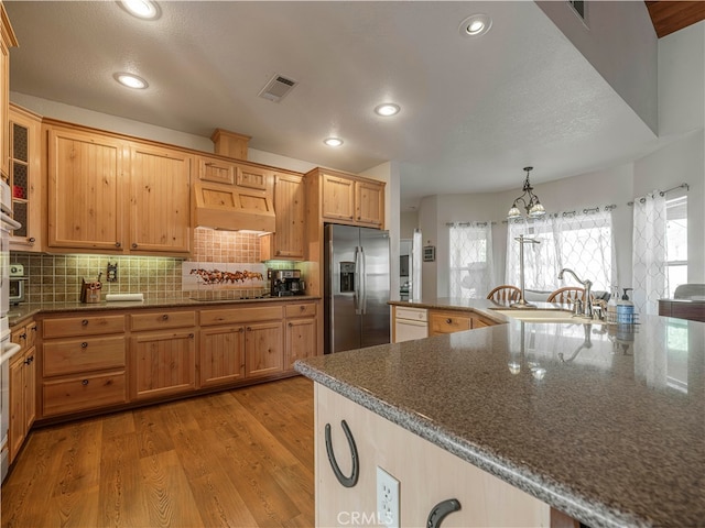 kitchen featuring stainless steel refrigerator with ice dispenser, sink, a notable chandelier, decorative light fixtures, and light hardwood / wood-style floors