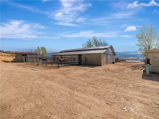 view of yard featuring a rural view, a mountain view, and an outbuilding