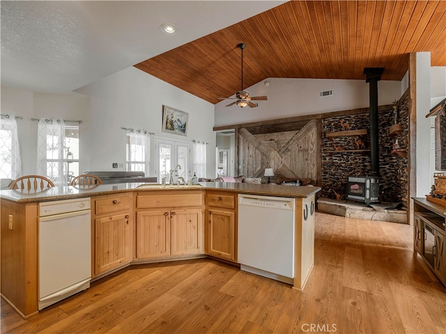 kitchen with a wood stove, white dishwasher, vaulted ceiling, light hardwood / wood-style floors, and ceiling fan