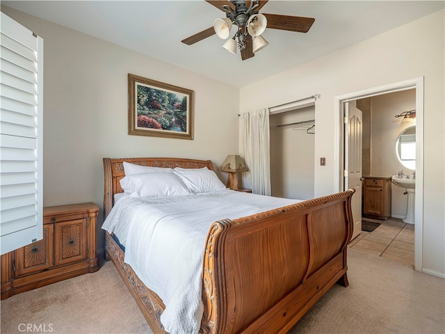 bedroom with a closet, ensuite bathroom, light colored carpet, and ceiling fan