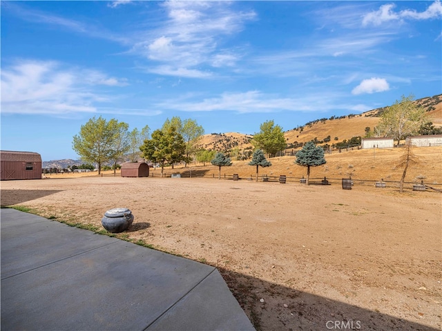 view of yard featuring a mountain view, a storage unit, and a rural view