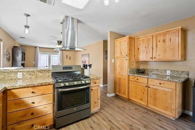 kitchen featuring gas range, light wood-type flooring, light brown cabinetry, island range hood, and light stone counters