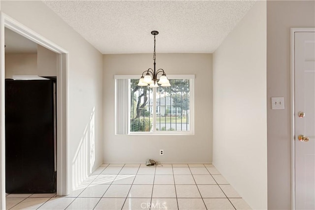 unfurnished dining area with a textured ceiling, light tile patterned floors, and a chandelier