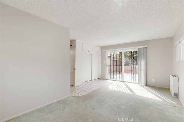 carpeted empty room featuring a textured ceiling and radiator heating unit