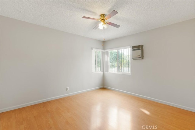 empty room featuring hardwood / wood-style flooring, ceiling fan, a textured ceiling, and a wall mounted AC