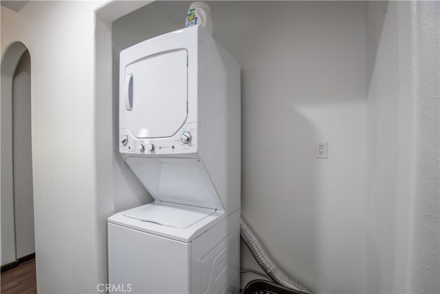 laundry room with stacked washer and clothes dryer and dark hardwood / wood-style flooring