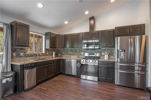 kitchen with sink, vaulted ceiling, appliances with stainless steel finishes, and decorative backsplash