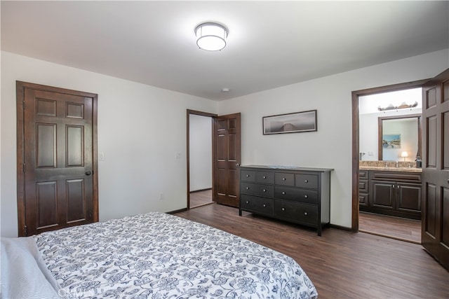 bedroom featuring dark wood-type flooring, ensuite bath, and sink