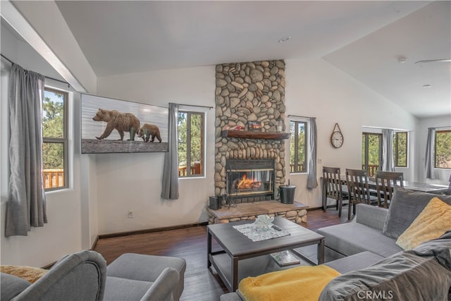 living room with dark hardwood / wood-style flooring, a stone fireplace, and vaulted ceiling