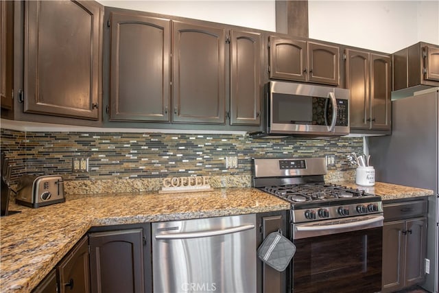 kitchen with appliances with stainless steel finishes, decorative backsplash, light stone countertops, and dark brown cabinets