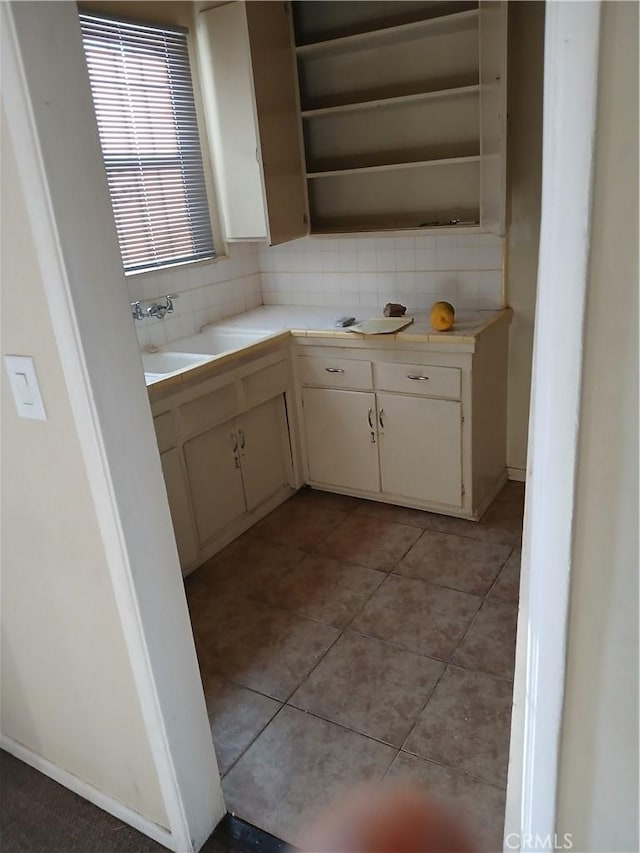 interior space with tasteful backsplash, cream cabinets, sink, and light tile patterned floors