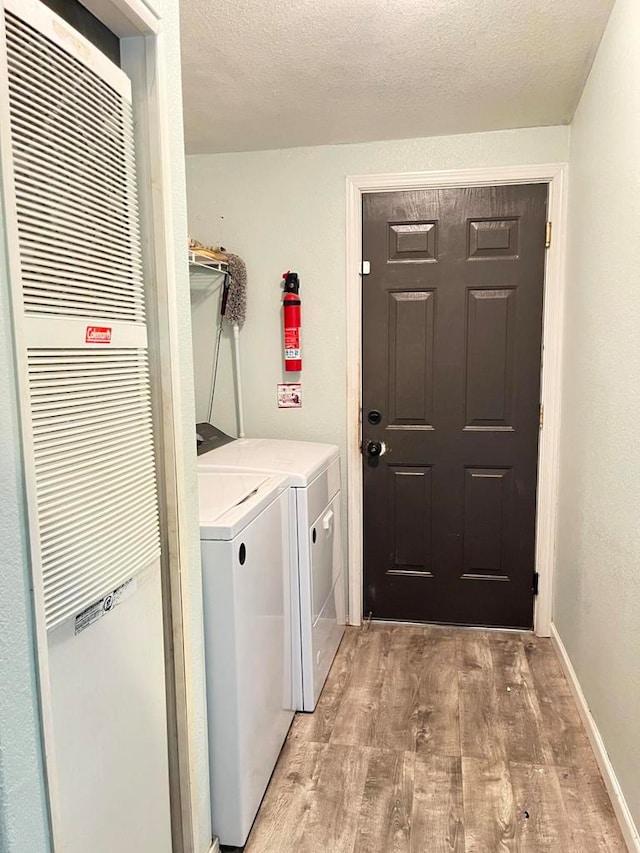 laundry area featuring light hardwood / wood-style flooring, a textured ceiling, and washer and clothes dryer