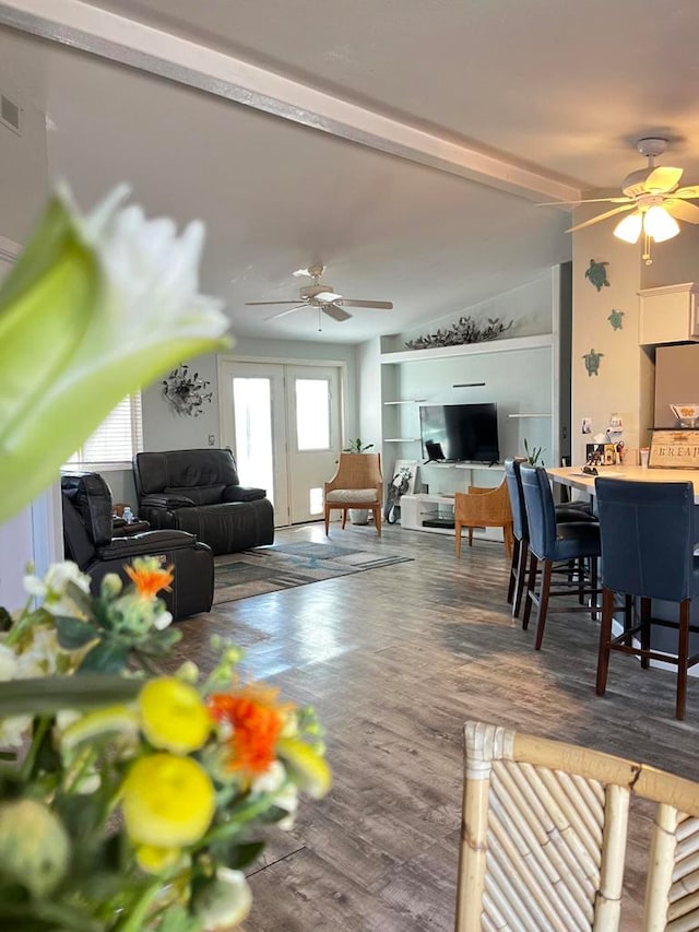 living room featuring hardwood / wood-style floors, vaulted ceiling with beams, and ceiling fan