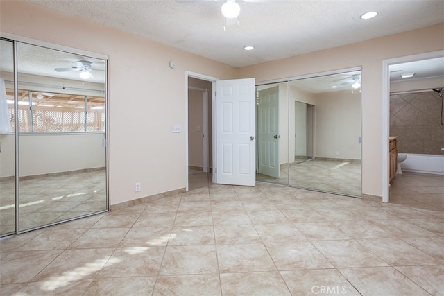 unfurnished bedroom featuring connected bathroom, a textured ceiling, light tile patterned floors, and ceiling fan