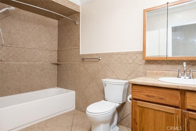 full bathroom with toilet, tile walls, vanity, tiled shower / bath combo, and tile patterned flooring