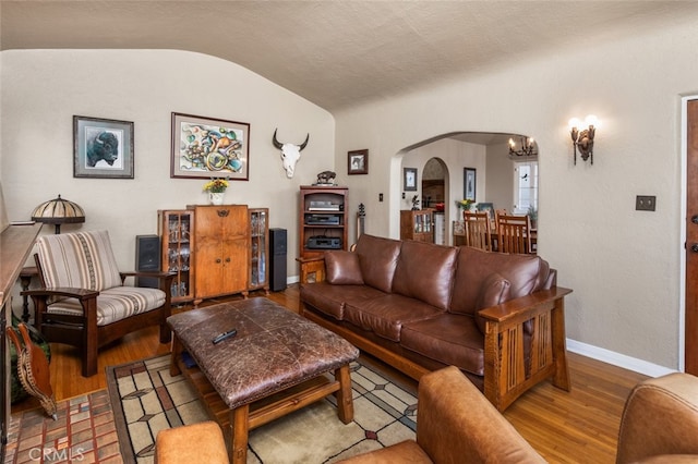 living room with a notable chandelier, lofted ceiling, and hardwood / wood-style floors