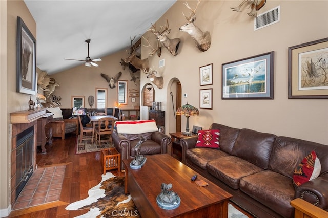 living room featuring a brick fireplace, hardwood / wood-style flooring, ceiling fan, and vaulted ceiling